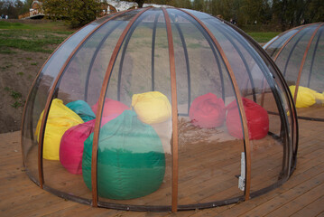 Transparent Igloo on a wooden terrace. Isolated premises for different companies. Protection from...