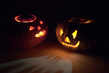 pumpkins for Halloween, turned to each other frightening faces, glowing in the dark with red and yellow mesmerizing light