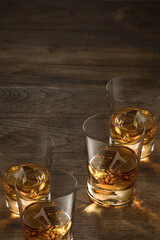 close up view of four glasses with ice and whiskey on wooden background