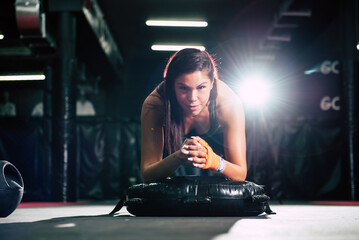 Fit woman working on abdominal muscles doing plank exercise, core workout at the gym