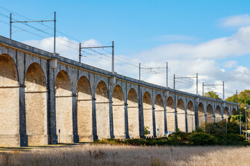Arches of the viaduct to the Loing canal bridge with railroad and overhead line. Seine-et-Marne department, Ile-de-France region, France.