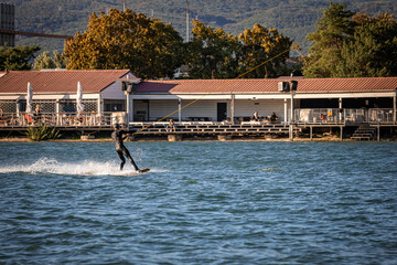 Fototapeta na wymiar Man being pulled on a wakeboard on a lake
