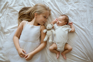 Little sister and her newborn brother. Toddler kid meeting new sibling. Cute girl and new born baby...