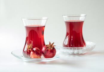 Turkish pomegranate tea in a glass cups isolated on white background, close-up. Traditional herbal tea with flowers and fruit of pomegranate in Turkey.