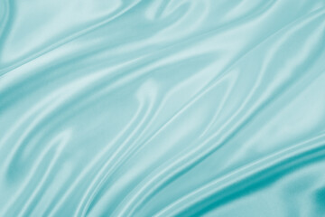 Photography of beautiful wavy turquoise silk satin luxury cloth fabric, abstract background design.