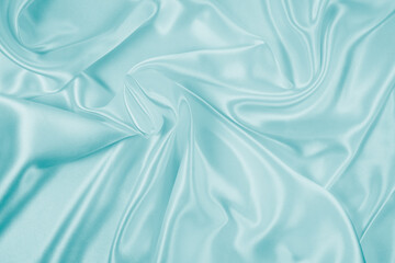 Obraz premium Photography of beautiful wavy turquoise silk satin luxury cloth fabric, abstract background design.