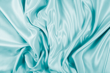 Obraz premium Photography of beautiful wavy turquoise silk satin luxury cloth fabric, abstract background design.