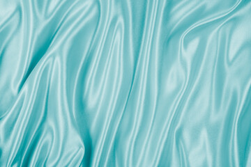 Photography of beautiful wavy turquoise silk satin luxury cloth fabric, abstract background design.