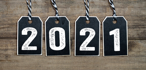 Black wooden hang tags with 2021 on weathered wood background