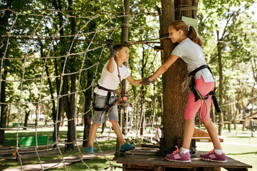 Little kids climbs on net in rope park, playground