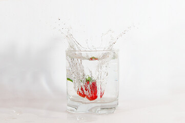 truskawki wpadające do szklanki z wodą