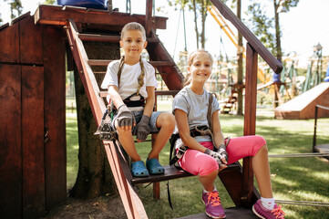 Little girl and boy sitting on stairs in rope park