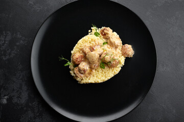 Boiled children's pasta stars with meatballs and microgreen, on a black background, place for text