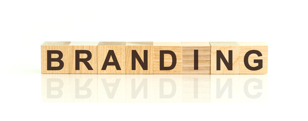 Wooden Blocks with the text: BRANDING. The text is written in black letters and is reflected in the mirror surface of the table.