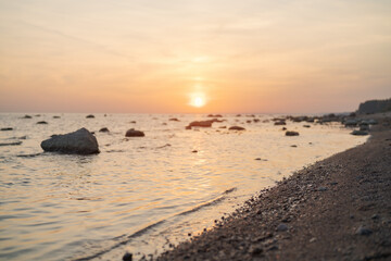 Fototapeta na wymiar Sunset on baltic sea beach with rocks in sand