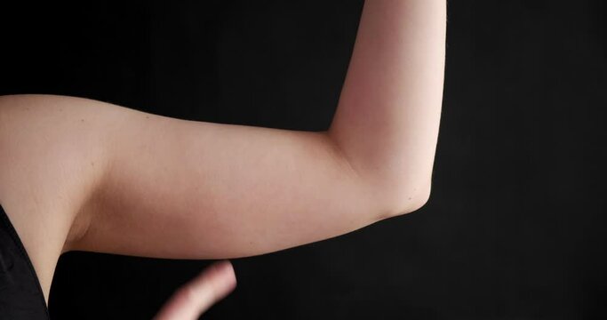 Chubby woman pinching upper arm fat isolated on blue background. Close up of caucasian female hand checking flabby skin. Body control, time to go on diet and weight loss concept