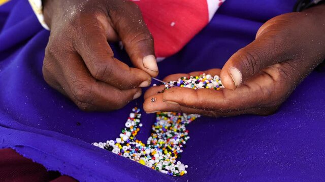 Making of handmade jewellery. Masai african women hands, top view, close up. Island of Zanzibar, Tanzania, East Africa