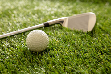 Golf stick and ball on green grass golf course, close up view.
