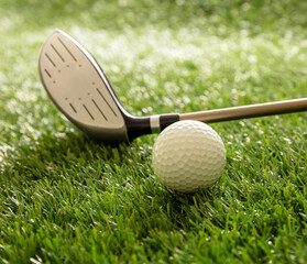 Golf stick and ball on green grass golf course, close up view.