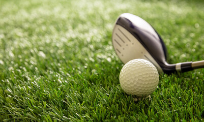 Golf club and ball on green grass golf course, close up view.