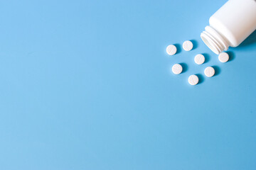 a jar with scattered medications pills on a blue background