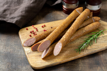 Smoked sausage. Sausages on a wooden serving Board on a brown wooden table. German sausages. Top view with a copy space