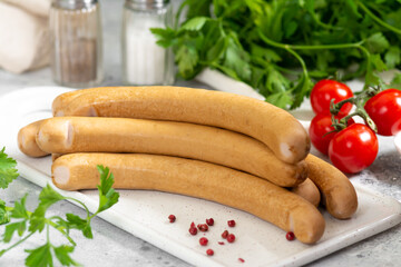Viennese sausages. Sausages on a white serving Board on a light gray table. German sausages