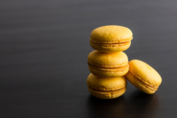 Fototapeta na wymiar Close-up of breakfast morning with yellow macaroons lemon taste. close-up of french dessert on the black background in a simple and beauty vintage composition. Food photography
