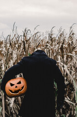 Scary Halloween man is holding his pumpkin head by his side  - obrazy, fototapety, plakaty