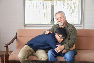 Senior Asian man embracing and listening to bad news from his son who just lost a job and come back home seeking for consolation and empathy from father with copy space