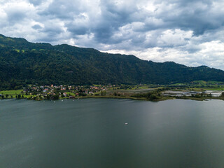 Fototapeta na wymiar Aerial view on Steindorf and the upper ends of Ossiacher Lake in Carinthia, Austria with its moor and marshlands on a summer day with great cloudscape.
