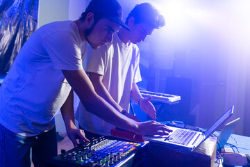 two Disc jockey or DJ stands behind the sound mixing console, makes sound at the party