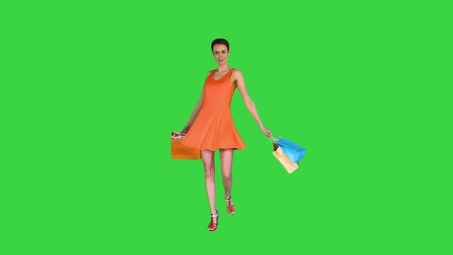 Beautiful girl shows bags with purchases turning around on a Green Screen, Chroma Key.