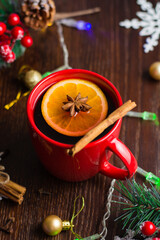 Delicious mulled wine alcoholic warm drink with cinnamon and star anise in a red cup. The concept of preparing for Christmas, warmth and comfort in the house, vertical format