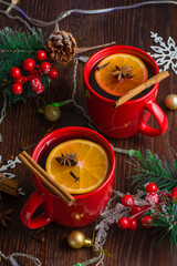 Aromatic, hot and delicious mulled wine with orange, cinnamon, star anise and cloves in red cups...