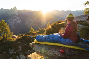 A woman enjoying breakfast from her bivouac on a beautiful morning in the mountains.