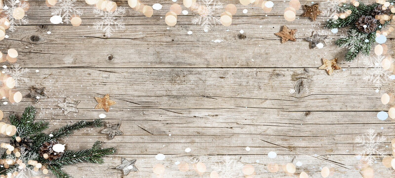 Festive decorative Christmas / Advent background - Christmas ornament corner border banner, with fir branches, stars, pine cone and bokeh lights - Above view on a rustic wood table background.