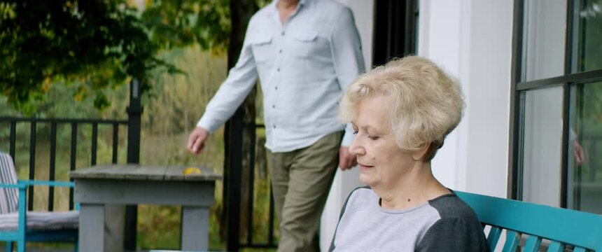 Elderly matue Caucasian husband joins his wife on a terrace of a house. Shot on RED cinema camera with 2x Anamorphic lens