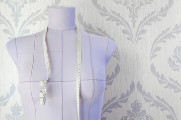 Lilac tailor's mannequin for sewing clothes and tape measure.
