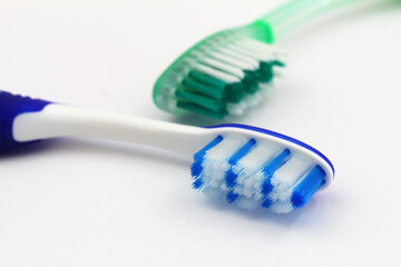 Closeup of two toothbrushes on white background
