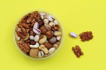 Selection of nuts in plastic box on yellow background
