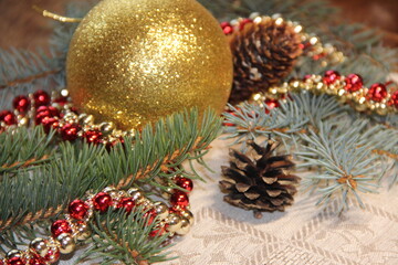 Golden ball, fir branches, cones and Christmas decorations on a gray background