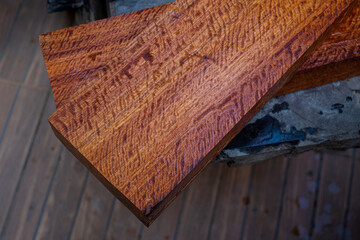 Burma padauk wood has tiger stripe or curly stripe grain on the table at blurred background