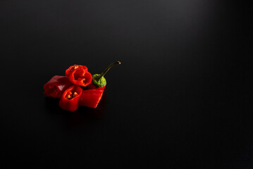 Fresh chili peppers, cut into pieces, lie on a black background. copyspace