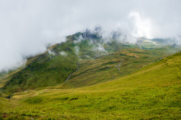 Fog covering a green hill on a summer day in the Valais Alps of Switzerland near First. 
