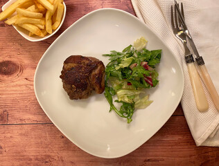 Beef rump steak fillet with french fries and green salad.