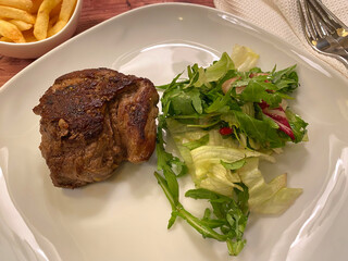 Beef rump steak fillet with french fries and green salad.