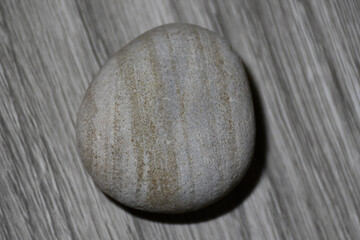 Rounded gray striped stone on a blurred gray surface with a similar pattern