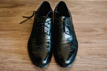Classic male black leather shoes isolated on a light brown. Wedding accessories groom on rustic wooden background. flat lay. top view.