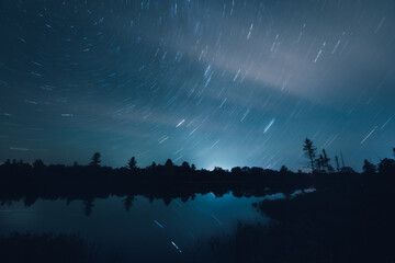 Nearly clear night skies as seen from Torrance Barrens dark sky reserve, Muskoka, Ontario, featuring star trails, lake, reflection and a little cloud